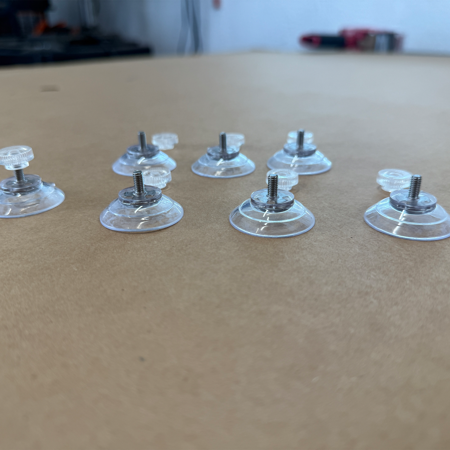 7 Clear suction cups with metal screws on a cardboard surface