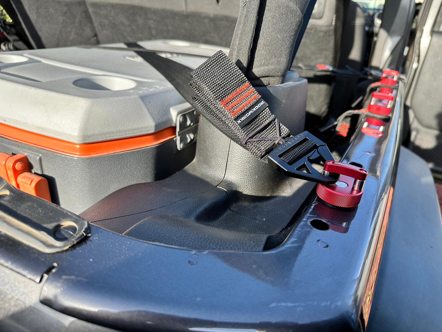 Tool box with Rockworkx tie strap in orange trim attached on a Jeep red hard top thumbscrew