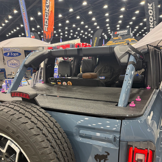 Back of Cactus Gray Bronco with JFTops cargo cover at an indoor event with banners in the background
