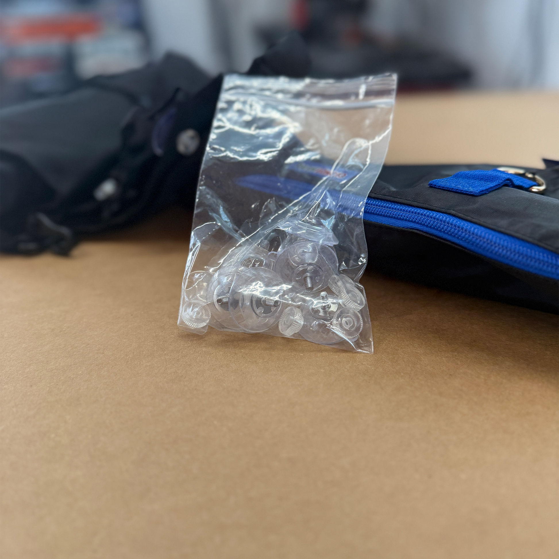 Clear plastic bag with 7 replacement suction cups on a brown surface with a blue and black Dash Poncho in the background.