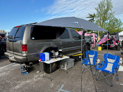 Display of 8x7 shade awning attached to side of a Ford Excursion at an event 