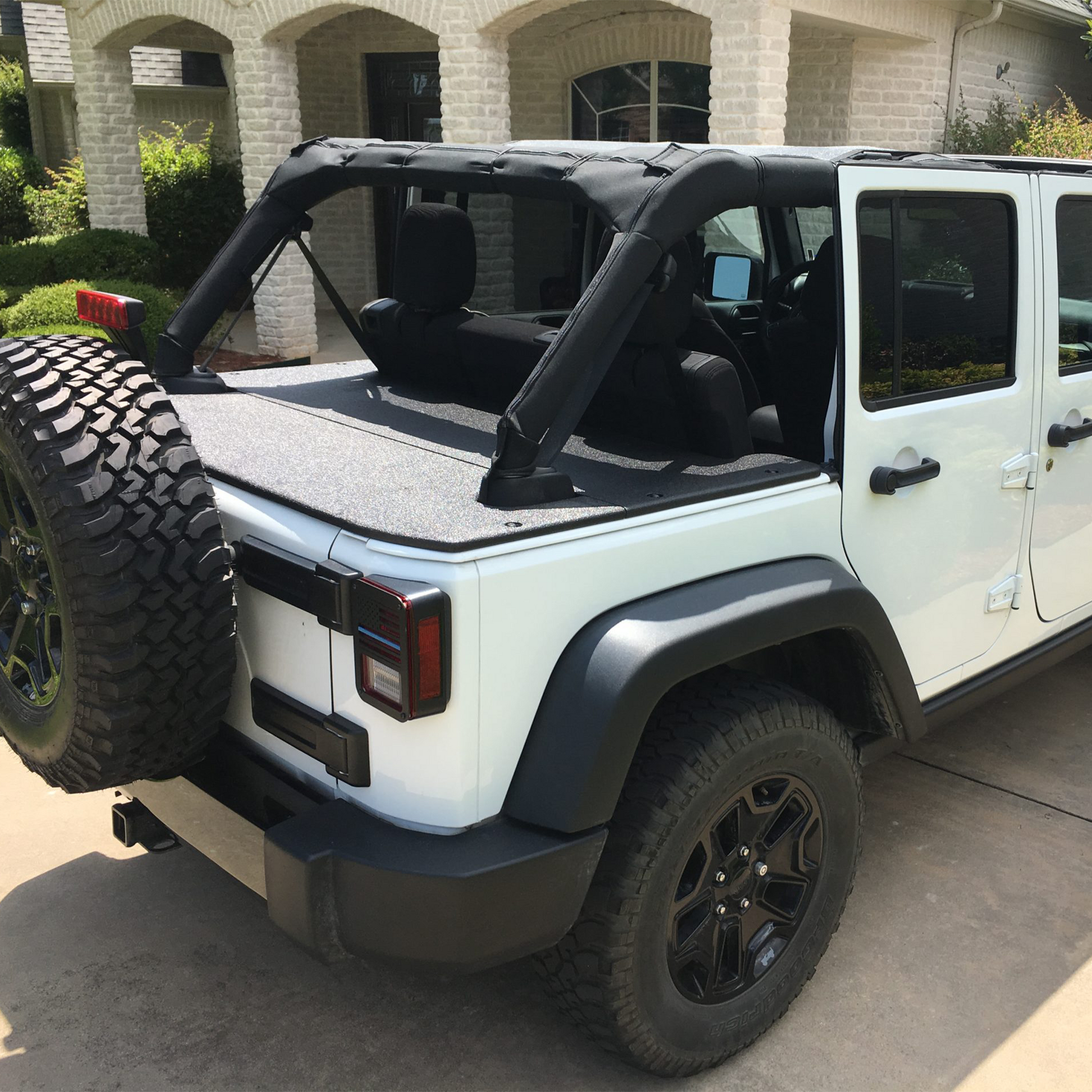 White Jeep Wrangler JKU with black sun screen and rhino lined cargo cover with tire on trunk