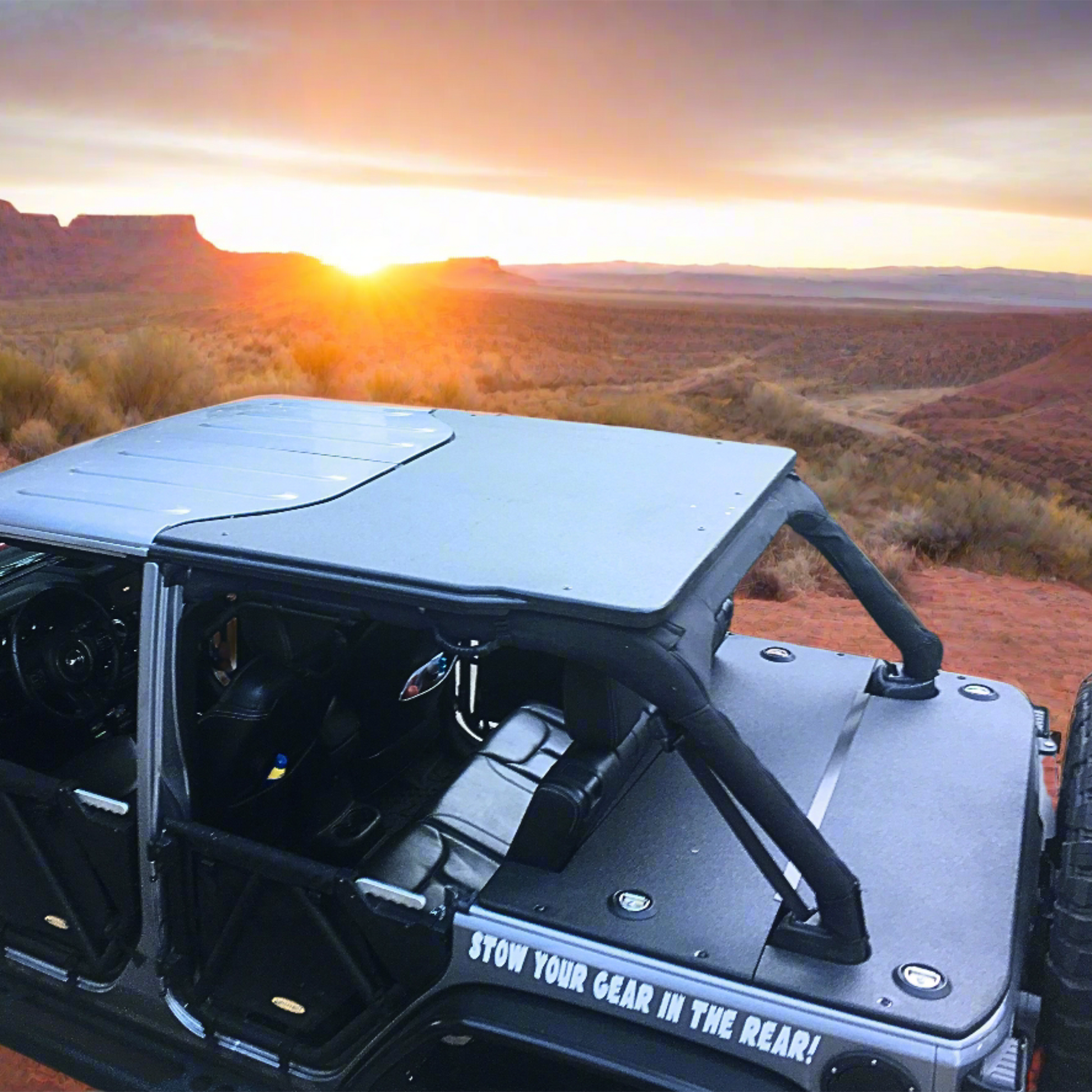 Open-top JKU Jeep in a desert landscape with sunset showcasing rhino lined JFTOPS cargo cover on trunk