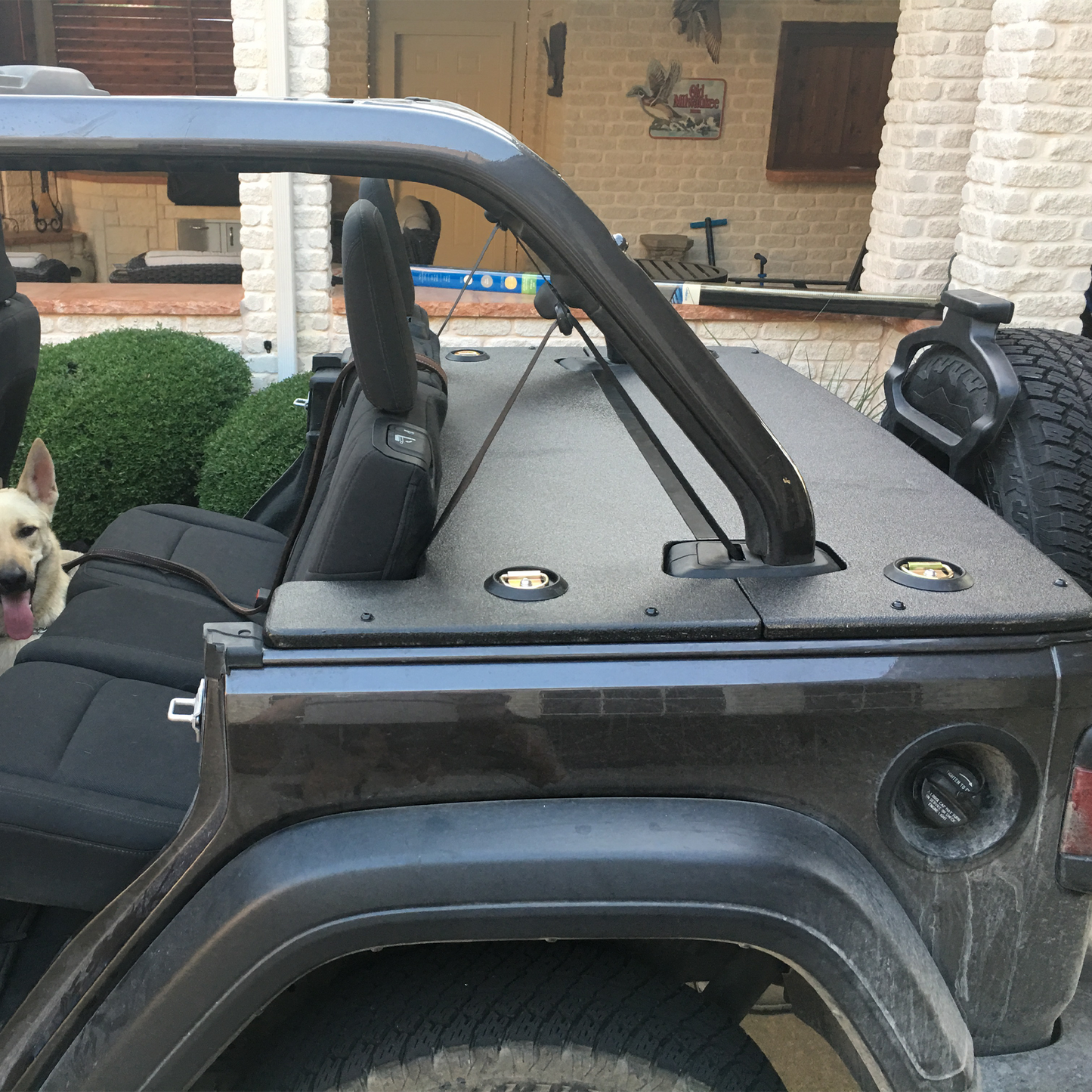 Close-up of a black JLU Wrangler with a dog in the background and JFTops cargo cover over trunk space