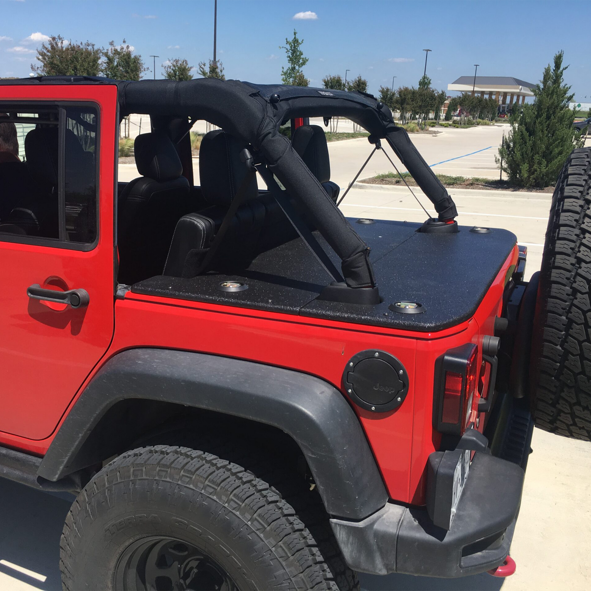 Red Jeep Wrangler  JKU with black hard top cargo cover on pavement