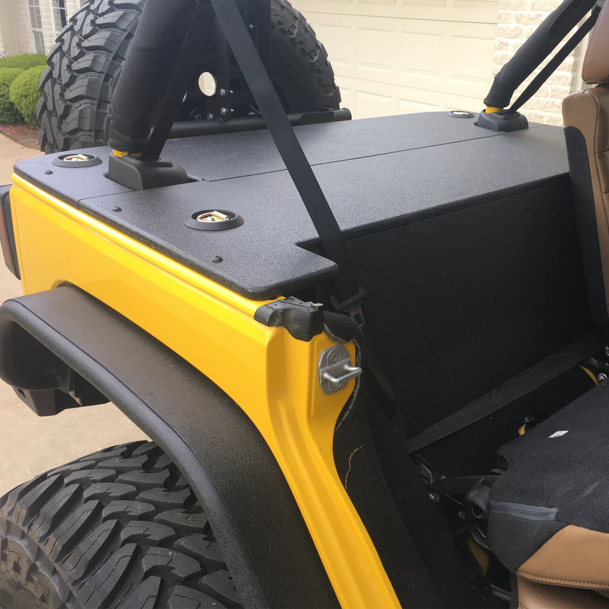 Yellow Jeep JKU with a spare tire mounted on the back and JFTops cargo cover rhino lined showing security board