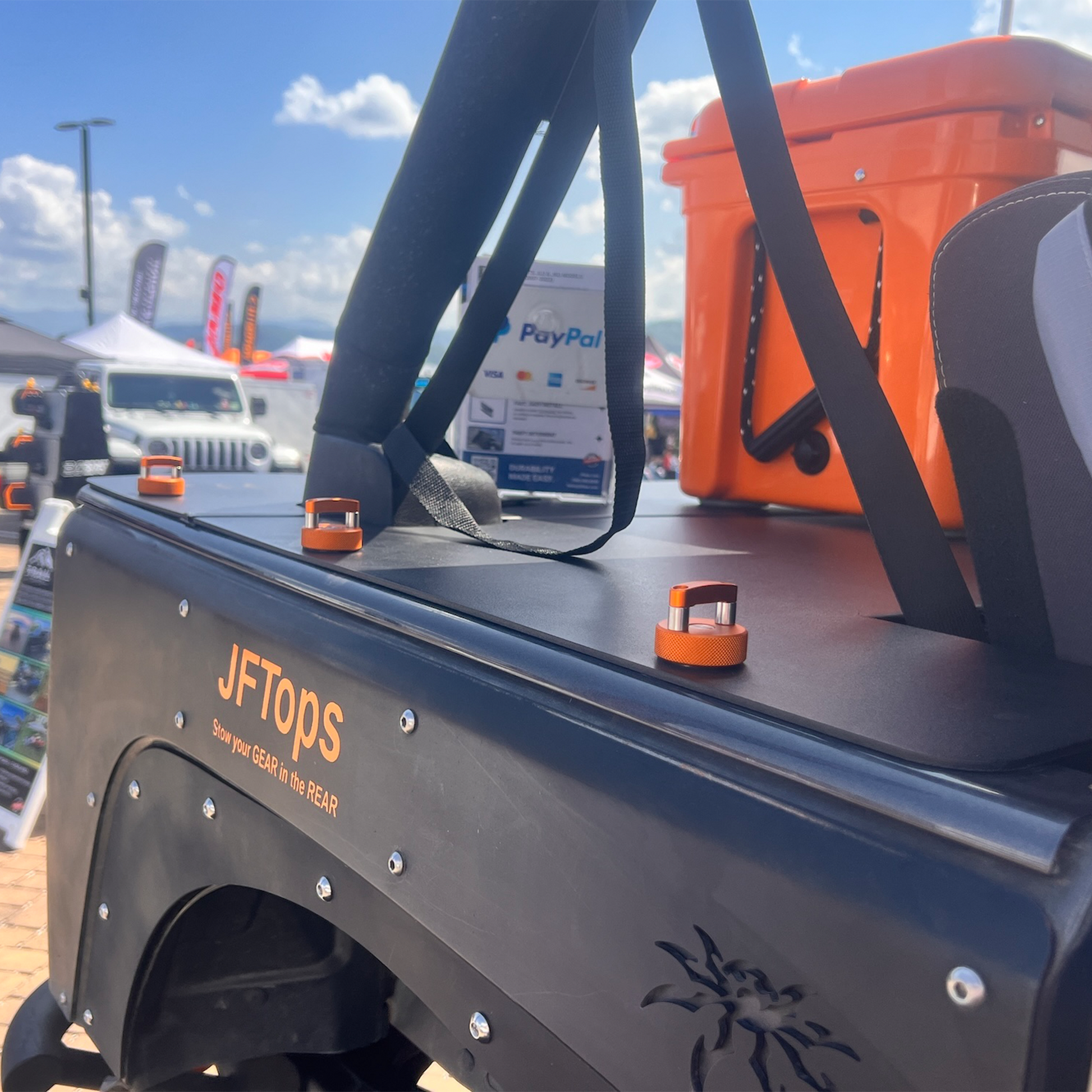 JFTops JKU Jeep cargo cover with an orange cooler in the background and Rockworkx orange hard top thumbscrews